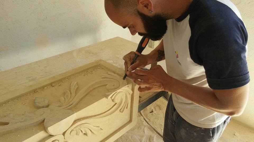 An artisan carving a piece of stone in a workshop.